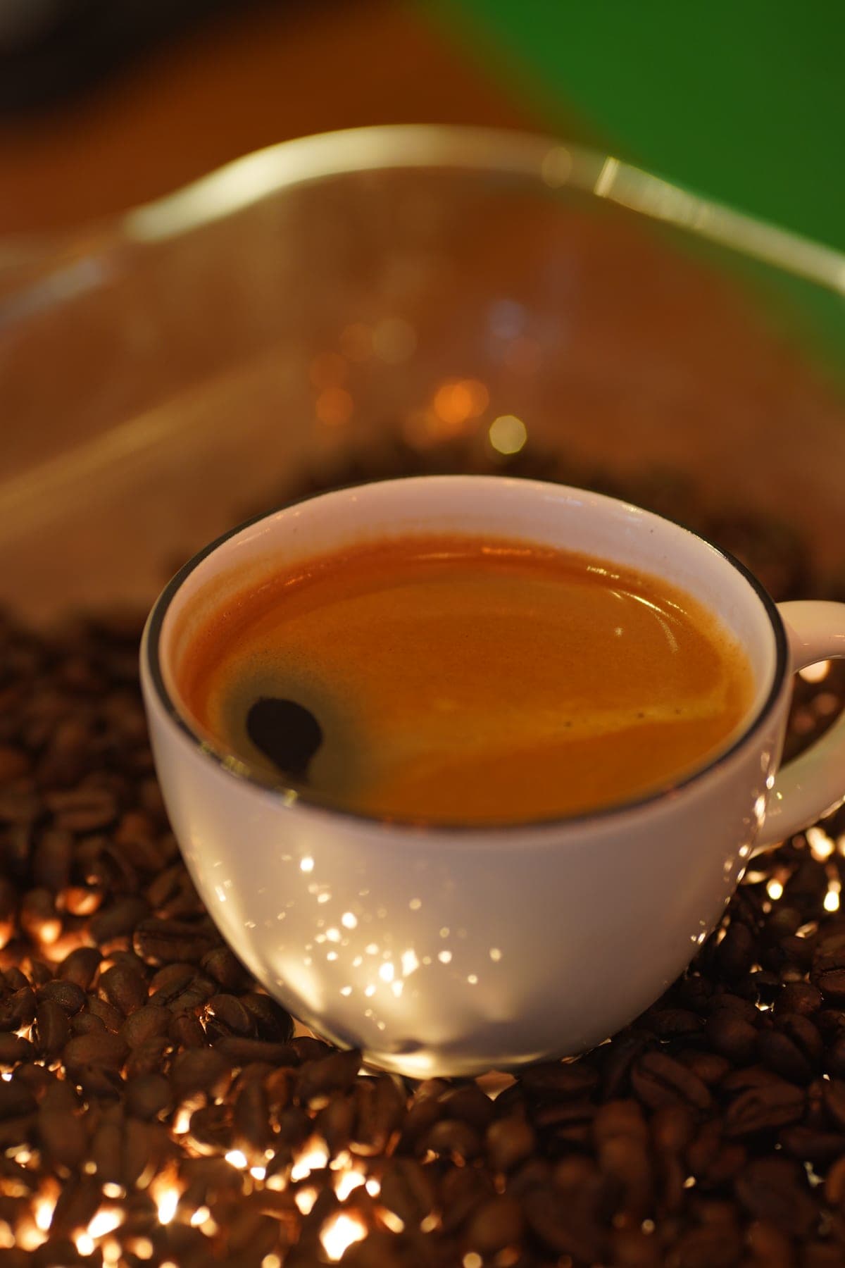 Beyaz fincanda espresso, çekirdekler üzerinde